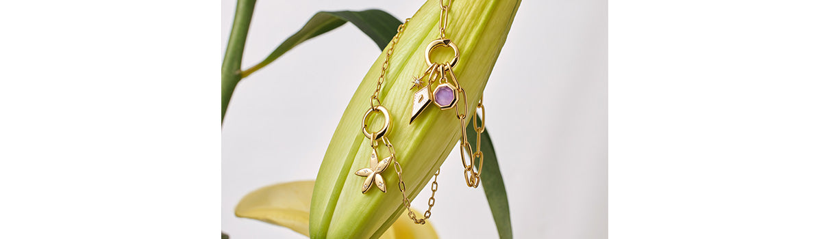 Gold curb chain with oval Amazonite flower charm and sterling silver puffy letter charms, accented by a gold sparkle flower charm, adorning a lily.